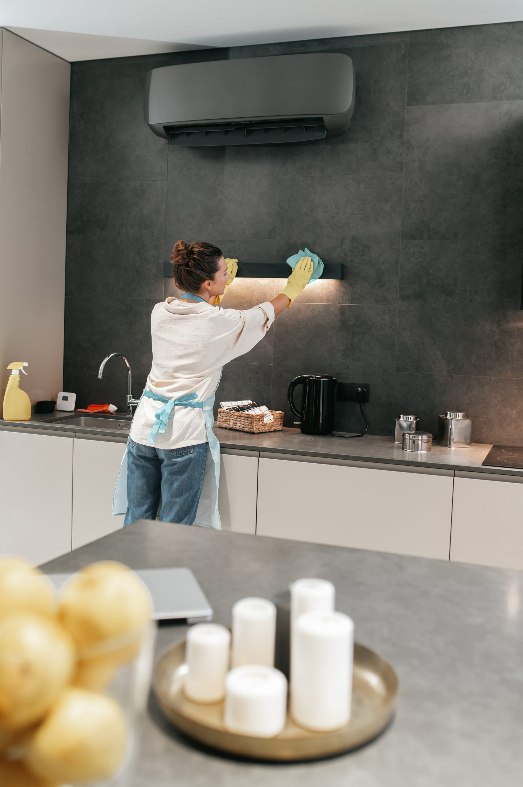 Housework. Young dark-haired woman cleaning the lamp in the kitchen